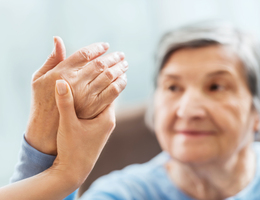 Someone holds an older woman's hand